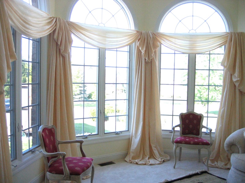Luxurious sheers pooling to the floor, swags around the bay.